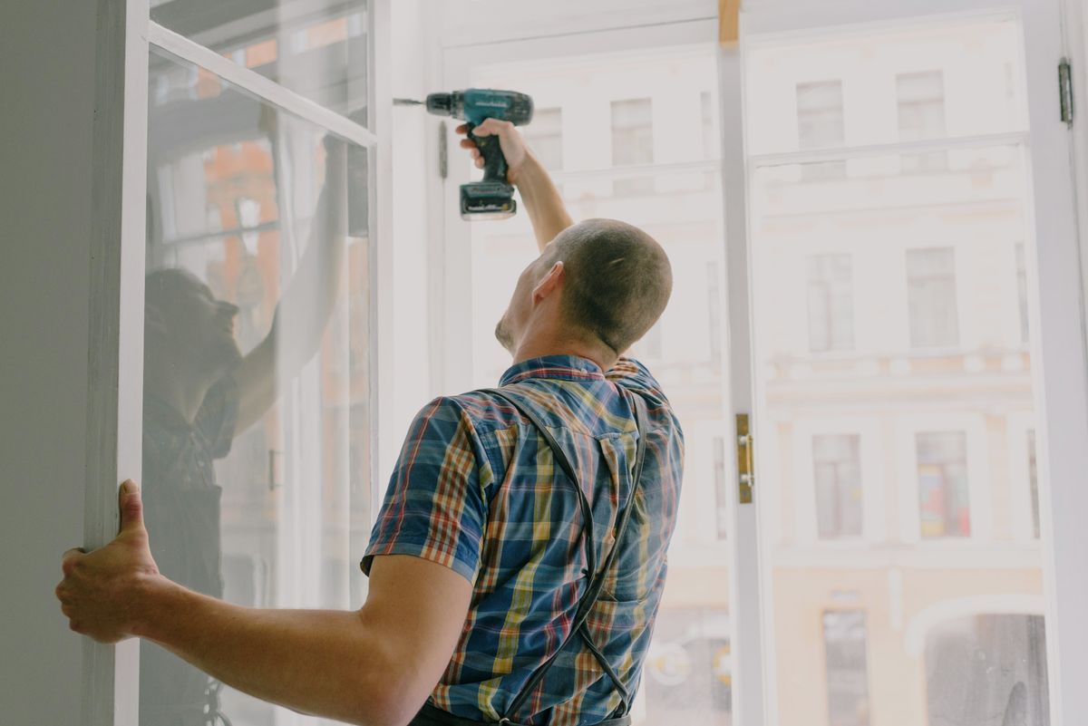 Worker drilling a new window frame into an opening